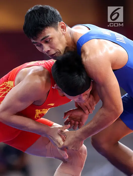 Pegulat putra Indonesia, Muhammad Aliansyah dan Zhang Gaoquan dari China saling mengunci saat bertarung pada kelas putra 67 Kg Asian Games 2018 di arena gulat JCC Senayan, Selasa (21/8). (Liputan6.com/Fery Pradolo)