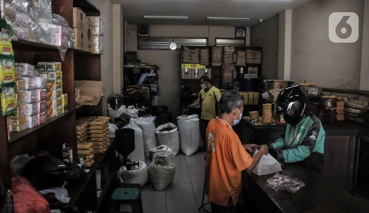 Pekerja melayani pembeli di toko kopi Sari Murni, Jatinegara, Jakarta Timur, Selasa (4/1/2021). Pengelola toko, Rudi berharap pandemi segera berakhir agar toko kopinya kembali ramai dan tetap bertahan mengharumkan kopi Nusantara. (merdeka.com/Iqbal S. Nugroho)