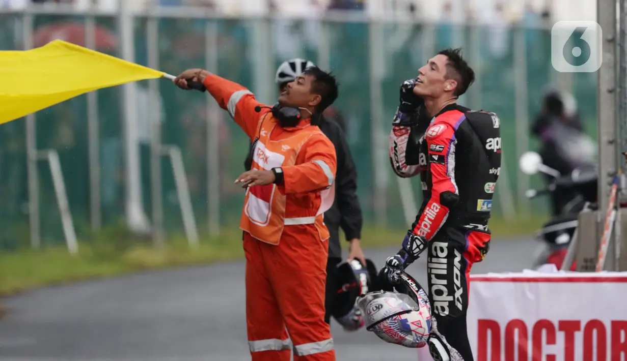 Pembalap Aprilia Racing, Aleix Espargaro (kanan) bersiap melemparkan helmnya ke penonton usai MotoGP seri Pertamina Mandalika International Street Sirkuit, NTB, Minggu (20/3/2022). Aksi ini untuk menepati janjinya setelah meraih sejuta pengikut akun instagramnya. (Liputan6.com/Helmi Fithriansyah)