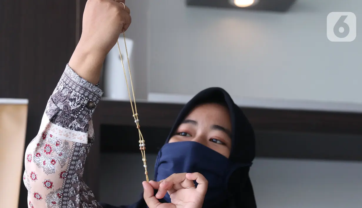 Petugas memeriksa perhiasan emas di Galeri 24 Pegadaian Kota Tangerang, Banten, Kamis (11/6/2020). Harga emas PT Aneka Tambang Tbk (Antam) pada hari ini naik Rp 12.000 menjadi Rp 893 ribu per gram dibanding sebelumnya. (Liputan6.com/Angga Yuniar)