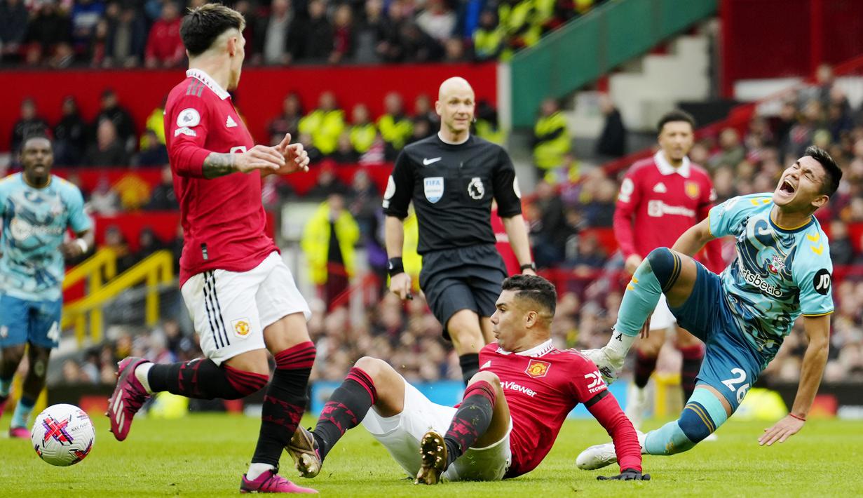 Pemain Manchester United, Casemiro, melakukan pelanggaran kepada pemain Southampton, Carlos Alcaraz pada laga Liga Inggris di Stadion Old Trafford, Minggu (12/3/2023). (AP Photo/Jon Super)