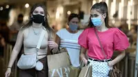 Pembelanja yang mengenakan masker meninggalkan toko di Oxford Street di pusat kota London, Senin (5/7/2021). PM Inggris Boris Johnson berencana mencabut sebagian besar pembatasan wilayah selama pandemi Covid-19, termasuk penggunaan masker dan jaga jarak mulai 19 Juli. (DANIEL LEAL-OLIVAS/AFP)