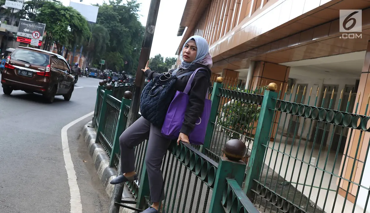 Penumpang melompati pagar pembatas untuk keluar dari Stasiun Cikini di Jakarta, Jumat (22/3). Jauhnya akses pintu masuk dan keluar stasiun menyebabkan sebagian orang mempersingkat waktu dengan melompat pagar pembatas. (Liputan6.com/Immanuel Antonius)