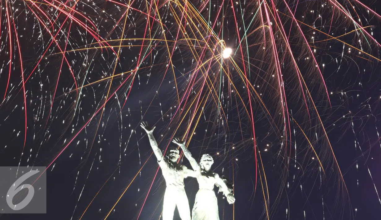 Patung monumen selamat datang dihiasi kembang api saat malam pergantian tahun di kawasan Bundaran HI, Jakarta, Sabtu (31/12). Ribuan warga yang memadati kawasan tersebut tak henti-hentinya meletupkan kembang api ke udara. (Liputan6.com/Immanuel Antonius)