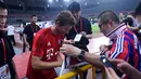 Penyerang Bayern Muenchen, Thomas Mueller menandatangani tanda tangan pengemar usai sesi latihan di Shanghai, China, (19/7/2015). Bayern mengunjungi Cina untuk menggelar Tur Pra-musim. (AFP PHOTO/JOHANNES EISELE)