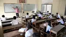 Siswa duduk di kelas dengan menjaga jarak saat memperhatikan guru mereka mengajar ketika sekolah dibuka kembali di Phnom Penh, Senin (7/9/2020). Sekolah-sekolah di Kamboja dibuka kembali pada Senin (7/9) setelah enam bulan ditutup akibat COVID-19. (TANG CHHIN Sothy /AFP)
