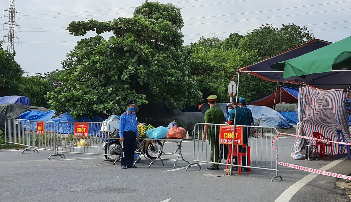 Polisi berjaga di belakang barikade yang didirikan untuk mengatur lalu lintas di Hanoi, Sabtu (24/7/2021). Vietnam memberlakukan penguncian wilayah (lockdown) selama 15 hari di ibu kota Hanoi mulai Sabtu ketika gelombang virus corona menyebar dari wilayah Delta Mekong selatan. (AP Photo/Hieu Dinh)