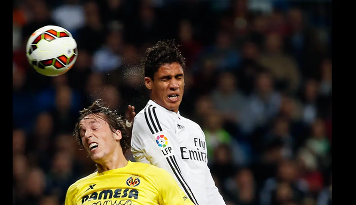 Bek Real Madrid, Raphael Varane (kanan) berebut bola di udara dengan gelandang Villarreal Tomas Pina pada laga Liga Spanyol di Santiago Bernabeu, Spanyol, (1/3/2015). Real Madrid bermain imbang dengan Villareal (1-1).  (Reuters/Susana Vera)