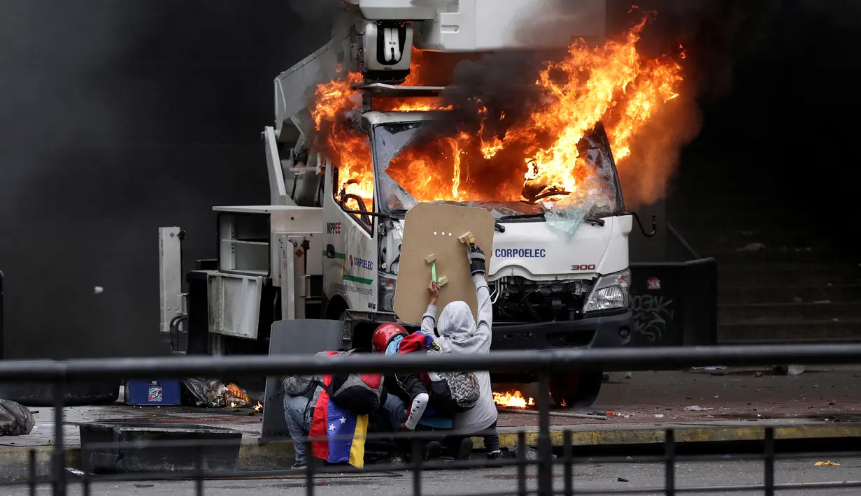 Para demonstran saat membakar sebuah mobil yang terpakir di depan Gedung Pengadilan Tinggi Venezuela di Caracas (7/6). (Reuters/Marco Bello)