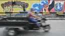 Pengendara melintas saat petugas Penanganan Prasaranan dan Sarana Umum (PPSU) menyelesaikan pembuatan mural di Jalan RE Martadinata, Tanjung Priok, Jakarta Utara, Selasa (24/5/2022). Pembuatan mural di sepanjang Jalan RE Martadinata yang dilakukan oleh petugas PPSU dari 19 kelurahan di Jakarta Utara tersebut dalam rangka menyambut balapan Formula E dan HUT ke-495 Kota Jakarta. (merdeka.com/Iqbal S Nugroho)