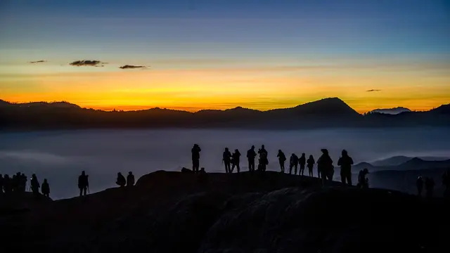 Wisatawan berdiri di puncak gunung berapi Bromo menunggu masyarakat suku Tengger mengantarkan sesaji ke kawah gunung berapi Bromo di Probolinggo, provinsi Jawa Timur, pada 30 Juni 2018