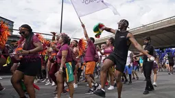 Sebuah pesta pora menari dengan para pemain selama Karnaval Notting Hill tahunan di London barat, Senin (29/8/2022). Karnaval yang kembali ke jalanan untuk pertama kalinya dalam dua tahun, setelah digagalkan oleh pandemi, adalah salah satu perayaan festival terbesar dari jenisnya di Eropa. (AP Photo/Alberto Pezzali)