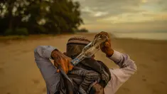 Tengku Mohamad Ali Mansor menyimpan botol kaca yang dia temukan di pantai dalam ranselnya saat matahari terbit di sebuah pantai di desa Mangkuk di distrik Setiu negara bagian Terengganu Malaysia timur pada 12 September 2020. (AFP/Mohd Rasfan)