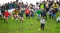 Peserta berlomba mengejar keju dalam kompetisi Cheese Rolling di Bukit Cooper, Gloucestershire, Inggris, Senin (27/5/2019). Acara ini awalnya dibuat oleh dan untuk penduduk lokal namun, kini ribuan orang datang dari berbagai penjuru dunia untuk menonton maupun berpartisipasi (Ben Birchall/PA via AP)