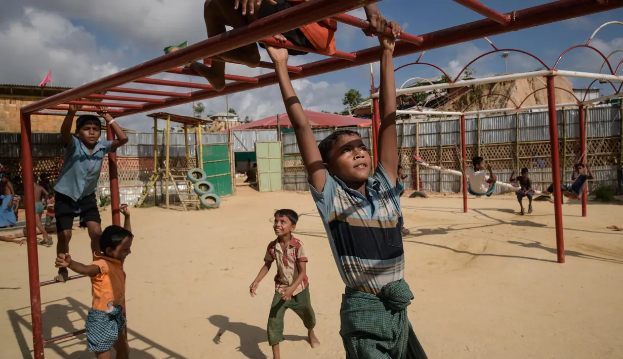 Anak-anak pengungsi Rohingya bergelantungan di tiang besi saat bermain di taman bermain kamp pengungsi Thangkhali, dekat Cox's Bazar, Bangladesh, Kamis (9/8). (Ed JONES/AFP)