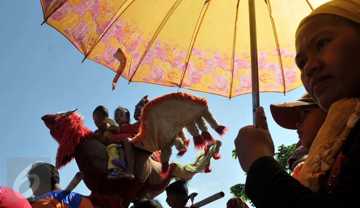 Seorang wanita melihat aksi dari pemain Sisingaan saat melewati ruas jalan di desa Jaya Bakti, Bekasi, Rabu (29/7/2015). Sisingaan adalah Tradisi Seni dari Kota Subang Jawa Barat. (Liputan6.com/JohanTallo)