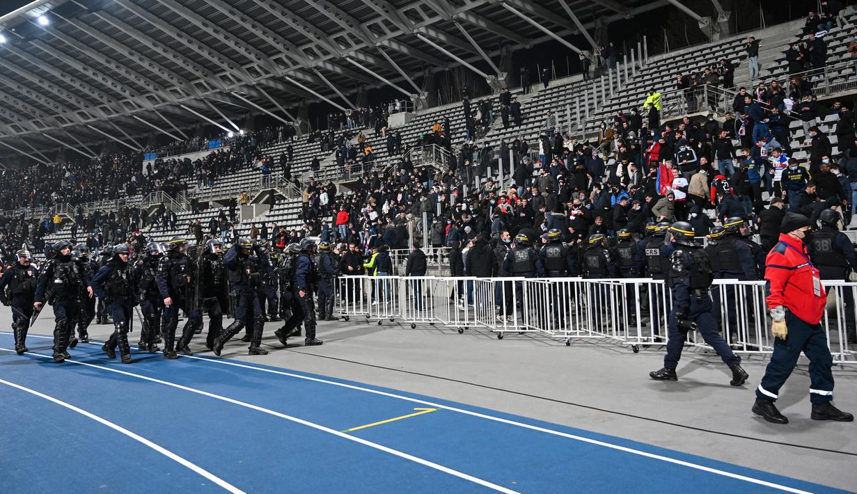 Polisi anti huru hara Prancis menghadapi penonton yang rusuh di babak pertama pertandingan 64 besar Piala Prancis antara Paris FC dan Olympique Lyon di stadion Charlety, Jumat (17/12/2021). Insiden ini menjadi yang kesekian kalinya kekerasan terus melanda sepakbola Prancis. (Bertrand GUAY/AFP)