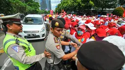 Petugas kepolisian membantu rekannya menertibkan demonstrasi ratusan bidan desa yang menutup akses jalan di depan gedung Kemenkes, Jakarta, Rabu (4/5). Para bidan tersebut menuntut diangkat menjadi pegawai tetap tanpa syarat.  (Liputan6.com/Yoppy Renato)
