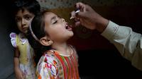 Seorang anak msaat diberikan vaksin polio oleh pekerja kesehatan di Lahore, Pakistan, (9/4). Pakistan meluncurkan vaksinasi polio baru, yang bertujuan agar 38,7 juta anak di bawah usia 5 tahun mendapatkan vaksin tersebut. (AP Photo/KM Chaudary)