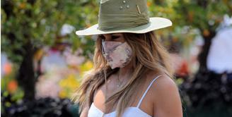 Saat berada di Montercarlo, Jennifer Lopez terlihat mengenakan spaghetti mini dress dipadukan dengan topi koboy dan handbag dari koleksi Valentino Garavani Roman Stud bag. CREDIT: Valentino