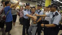 Polisi menahan  penumpang yang marah yang mencoba untuk bertarung dengan para pengunjuk rasa di Hong Kong, Selasa (30/7/2019). Para Pengunjuk rasa telah mengganggu layanan kereta bawah tanah pada pagi hari. (AP Photo/Vincent Yu)