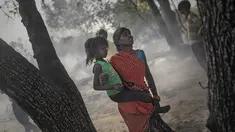 Seorang wanita menggendong putrinya saat terjadi kebakaran di daerah kumuh di Noida, pinggiran New Delhi, India, Minggu (11/4/2021). Dua anak tewas dan lebih dari 150 gubuk kumuh yang sebagian besar dihuni oleh para pemulung dalam kebakaran pada Minggu sore. (AP Photo/Altaf Qadri)