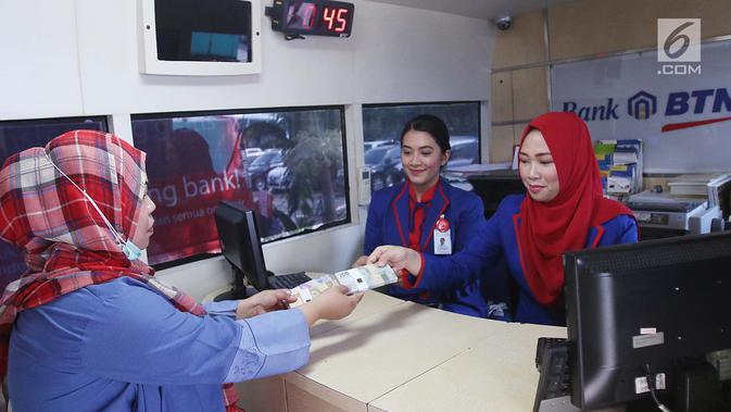 Seorang wanita menukarkan uang pecahan kecil pada mobil kas keliling Bank BTN di Lapangan IRTI Monas, Jakarta, Rabu (7/6). Bank Indonesia bekerja sama dengan 13 bank lainnya melayani penukaran uang hingga 16 Juni mendatang. (Liputan6.com/Angga Yuniar)