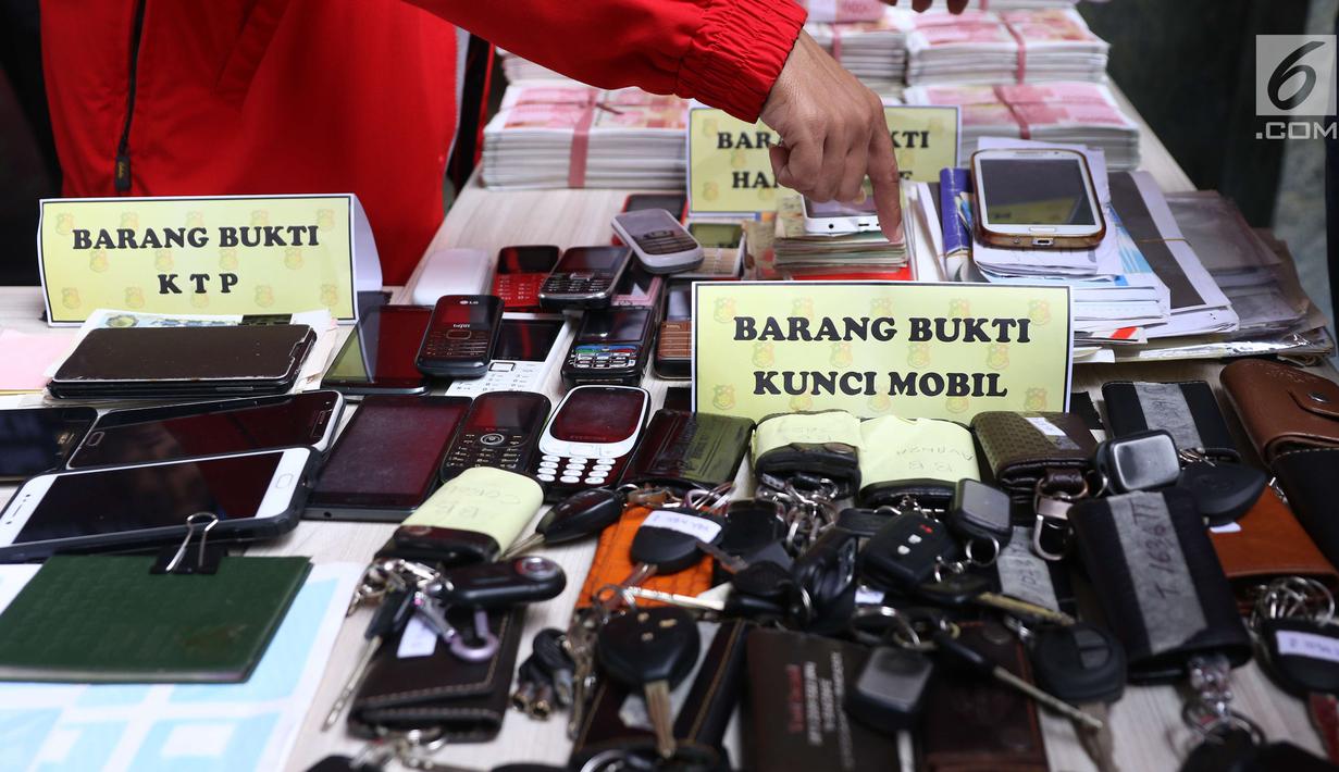 Petugas menunjukkan barang bukti saat rilis kasus pemalsuan dokumen dan uang palsu di Jakarta, Rabu (20/12). Bareskrim Polri menangkap sebanyak 13 tersangka yang mulai beroperasi sejak 2014 di wilayah Jakarta dan Jawa Barat. (Liputan6.com/Angga Yuniar)