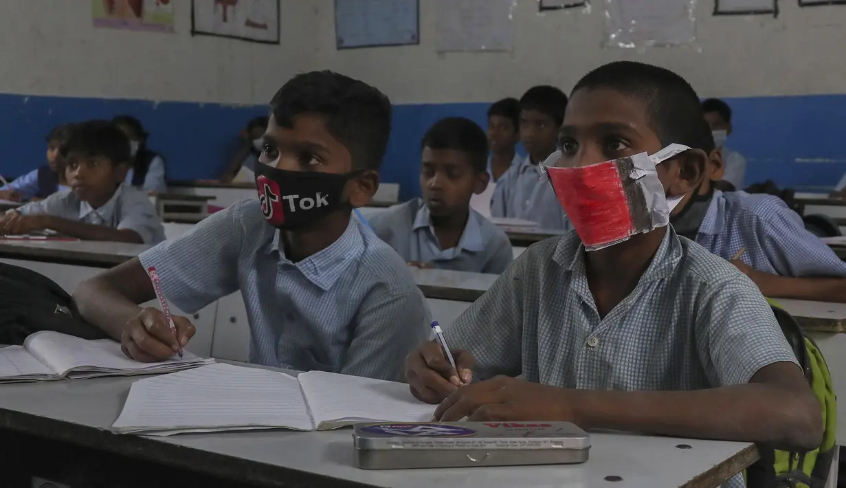 Sejumlah siswa mengenakan masker saat prose belajar mengajar di sebuah sekolah pemerintah di Hyderabad, India, Rabu (4/3/2020). Beberapa siswa memakai masker yang dibuat sendiri, dari kain maupun dari kertas. (AP Photo/Mahesh Kumar A.)