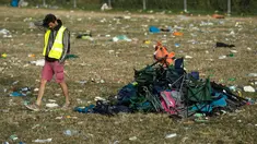 Seorang pria melewati kursi lipat dekat Pyramid Stage pada akhir Festival Glastonbury di arena Worthy Farm, Inggris, 26 Juni 2017. Penyelenggaraan festival musik terbesar di dunia itu menyisakan sampah yang berserakan di seluruh arena. (OLI SCARFF/AFP)