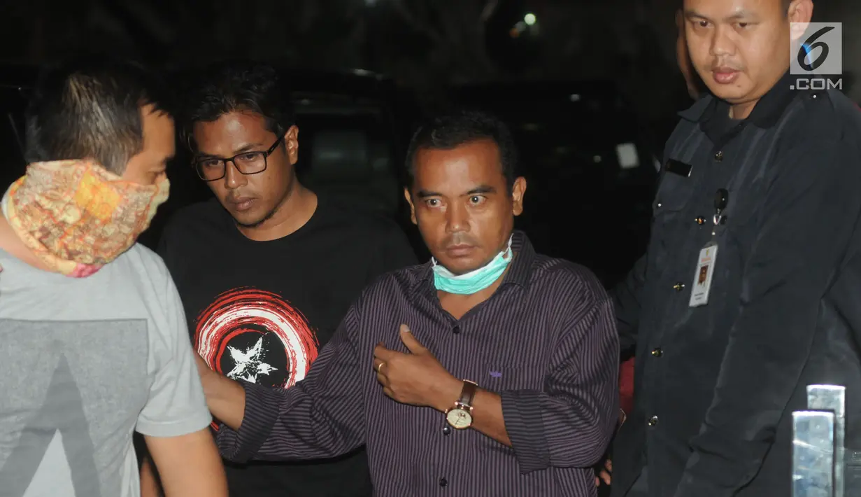 Bupati Purbalingga Tasdi (kemeja ungu) dikawal oleh petugas KPK menuju ruang pemeriksaan, Jakarta, Selasa (5/6). Tasdi dibawa tim penyidik KPK ke Jakarta dengan menggunakan kereta api ini sempat memperlihatkan salam metal. (Merdeka.com/Dwi Narwoko)