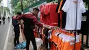 Suporter melihat atribut Persija di kawasan Senayan, Jakarta, Minggu (9/12). Pedagang memanfaatkan momen pertandingan Persija Jakarta yang akan bertanding melawan Mitra Kukar. (Liputan6.com/Faizal Fanani)