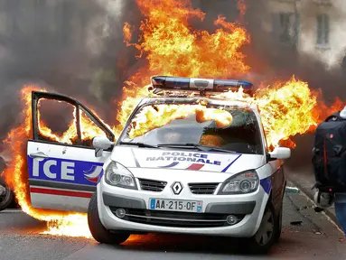 Sebuah mobil polisi terbakar saat demonstrasi buruh di Paris, Prancis (18/5). Demo buruh tersebut menentang kekerasan polisi dan melawan reformasi hukum yang berakhir bentrok dengan polisi. (REUTERS / Charles Platiau)