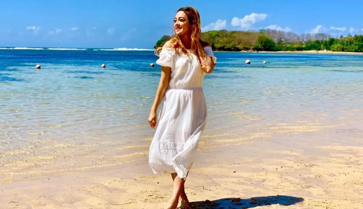 Wanita kelahiran Malang ini tampil sangat memukau saat liburan di Bali. Berpose dengan pakaian serba putih, rambutnya yang berwarna kekuningan tampak bercahaya. Cahaya matahari dan air laut berwarna biru sebagai latar belakang melengkapi penampilannya. (Liputan6.com/IG/@reisabrotoasmoro)
