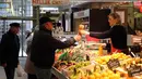 Orang-orang tanpa masker di sebuah pasar di Biarritz, Prancis barat daya, Senin (14/3/2022). Prancis telah mencabut sebagian besar pembatasan COVID-19 pada Senin, dan mengizinkan mereka yang tidak divaksinasi kembali ke restoran, olahraga arena dan tempat rekreasi lainnya. (AP Photo/Bob Edme)