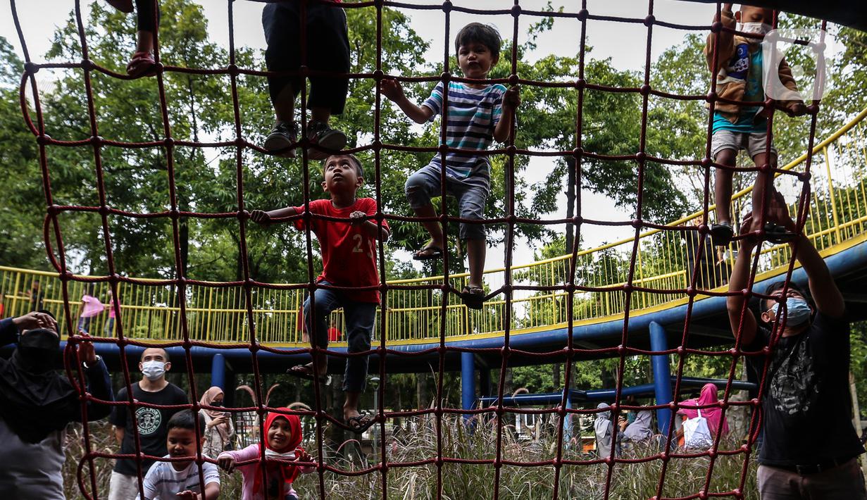 Anak-anak didampingi orang tua mereka bermain di Taman Puring, Jakarta, Minggu (9/1/2022). Di tengah ancaman penyebaran covid-19 varian Omicron dan pemberlakukan PPKM level 2, masyarakat tetap melakukan aktivitas pada akhir pekan di luar rumah. (Liputan6.com/Johan Tallo)