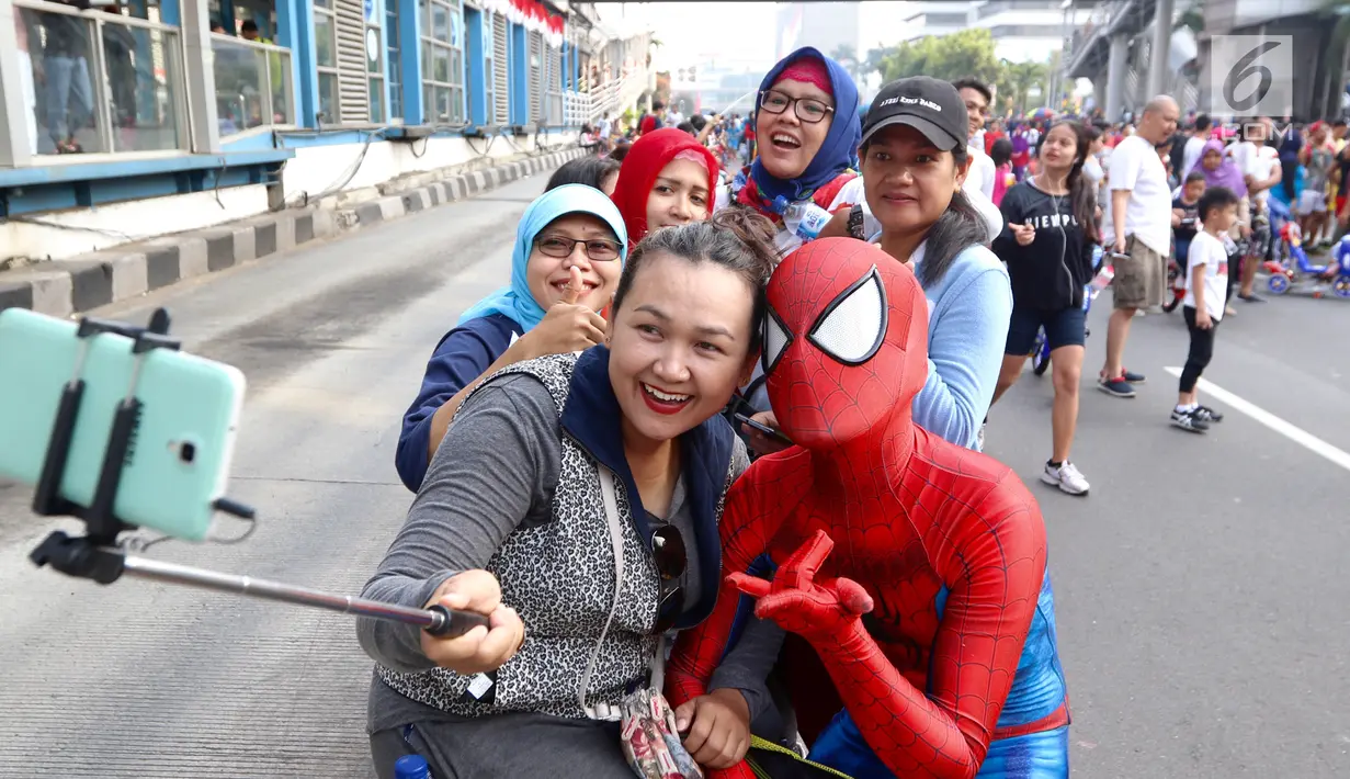 Ibu-ibu berswafoto dengan seorang yang kenakan kostum Spiderman pada acara amal di  CFD Jalan MH Thamrin, Jakarta, Minggu (6/8). Kegiatan tersebut untuk membantu anak-anak Panti Asuhan Muslimin Jaya. (Liputan6.com/Fery Pradolo)