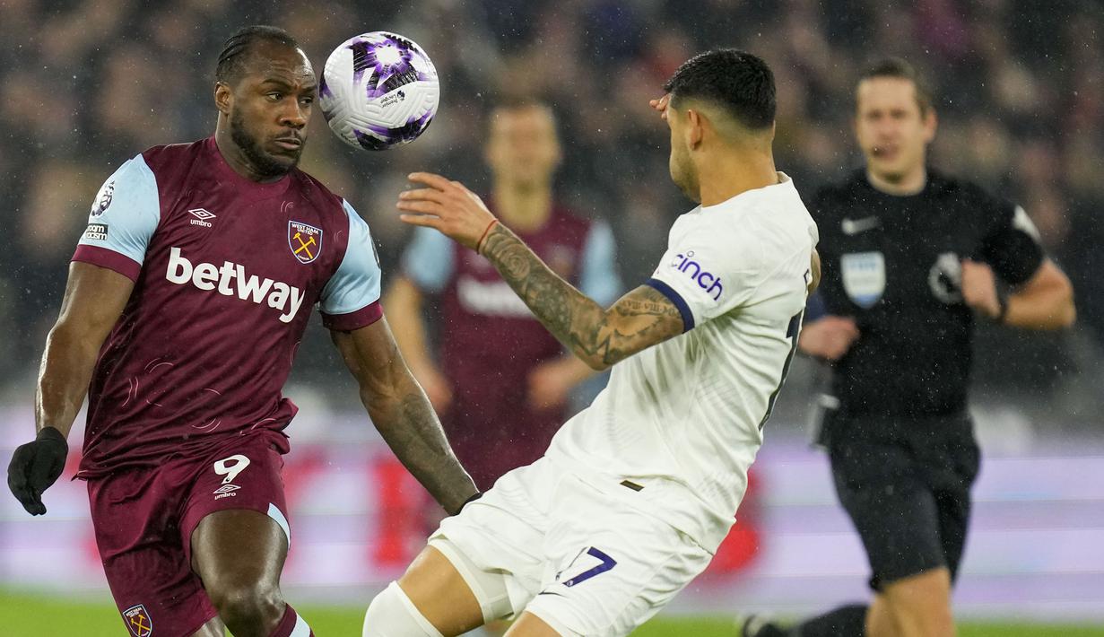Gelandang West Ham United, Michail Antonio (kiri) berusaha mengontrol bola di depan bek Tottenham Hotspur, Cristian Romero pada laga pekan ke-31 Premier League 2023/2024 di London Stadium, London, Selasa (2/4/2024) malam. (AP Photo/Kirsty Wigglesworth)