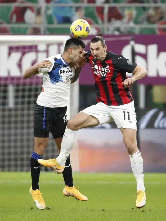 Penyerang AC Milan, Zlatan Ibrahimovic berebut bola udara dengan bek Atalanta, Cristian Romero pada pertandingan lanjutan Liga Serie A Italia di Stadion San Siro, Minggu (24/1/2021). AC Milan tumbang atas Atalanta dengan skor telak 0-3. (AP Photo/Antonio Calanni)