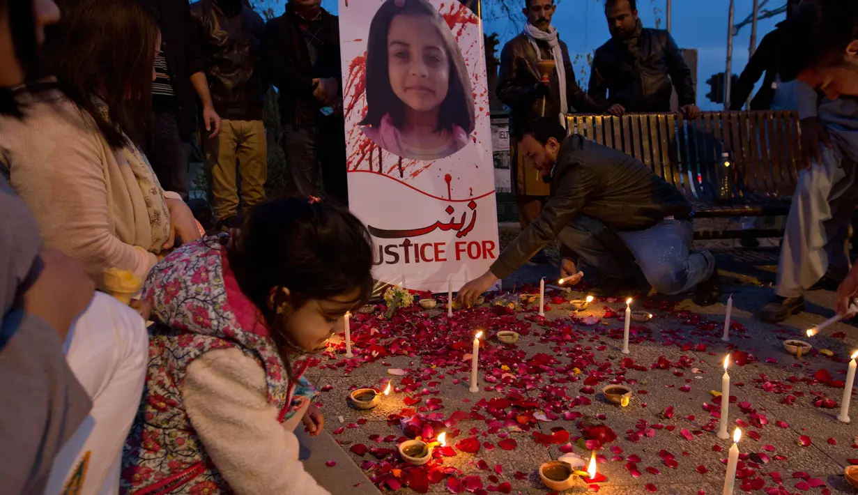 Seorang anak menaruh lilin untuk  Zainab Ansari, gadis 8 tahun yang diculik, diperkosa dan dibunuh di Islamabad, Pakistan (11/1). Sampai saat ini pelaku belum ditangkap. (AP Photo/B.K. Bangash)