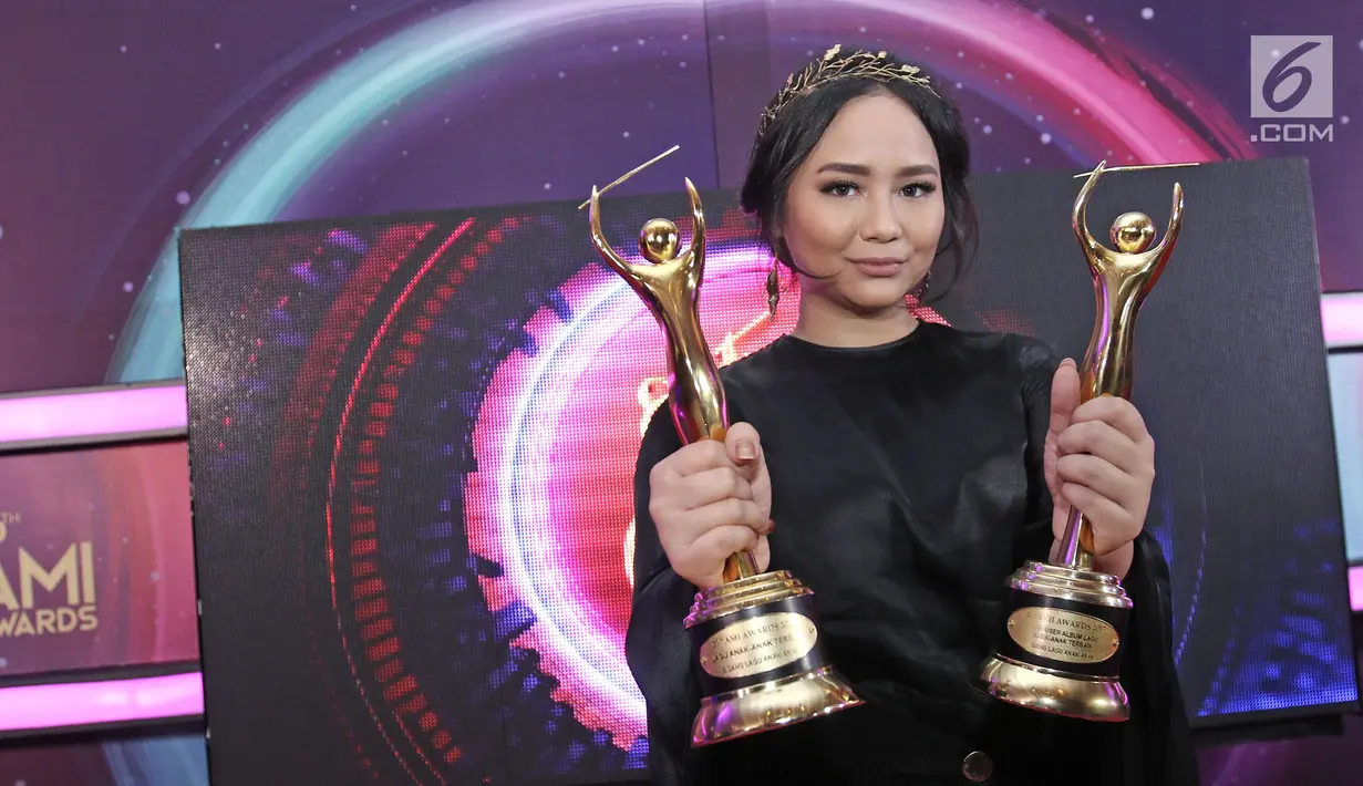 Penyanyi Gita Gutawa berpose memenggang piala usai meraih penghargaan Anugerah Musik Indonesia (AMI) Awards 2017 di Teater Garuda TMII, Jakarta, Kamis (16/11). (Liputan6.com/Herman Zakharia)