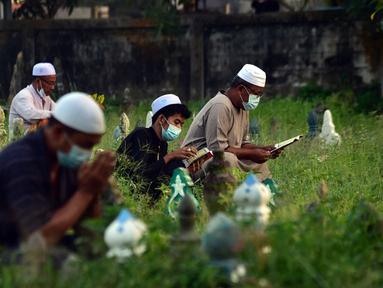 Orang-orang berdoa di sebelah makam kerabat saat perayaan Hari Raya Idul Adha di sebuah pemakaman di Provinsi Narathiwat, Thailand, Rabu (21/7/2021). Setiap Idul Adha atau hari besar Islam lainnya, sebagian warga banyak mendatangi kuburan untuk mendoakan keluarganya. (Madaree TOHLALA/AFP)