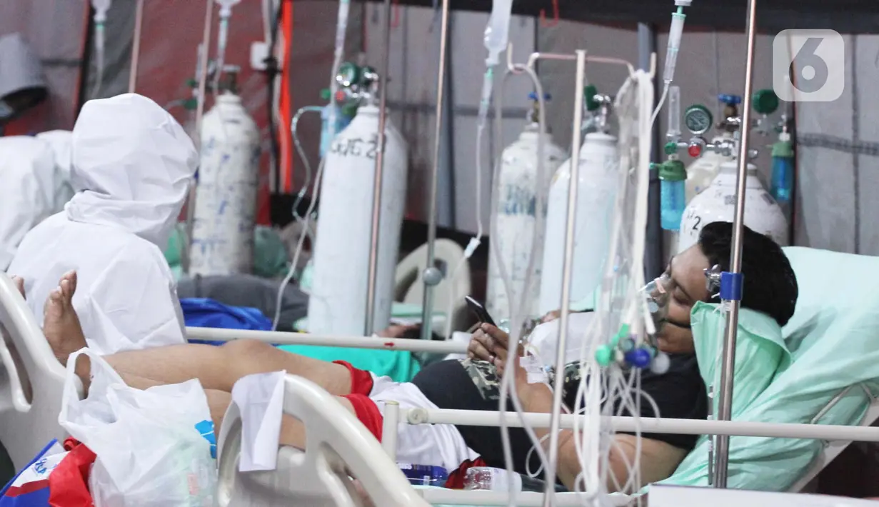 Pasien yang terpapar Covid-19 melihat ponsel saat di dalam tenda darurat yang didirikan di RSUP dr Sintanala, Kota Tangerang, Rabu (30/6/2021). Tenda Darurat di RSUP dr. Sintanala langsung penuh hingga pasien yang terus berdatangan harus mengantri sampai keluar tenda. (Liputan6.com/Angga Yuniar)