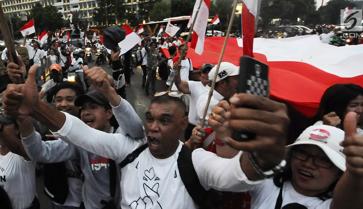 Sejumlah pendukung capres-cawapres 01 Jokowi-Ma'ruf Amin membentangkan bendera merah putih di kawasan bunderan HI, Jakarta, Rabu (17/4). Pendukung capres-cawapres 01 arak-arakan merayakan unggul dalam versi hitungan cepat. (Liputan6.com/Herman Zakharia)