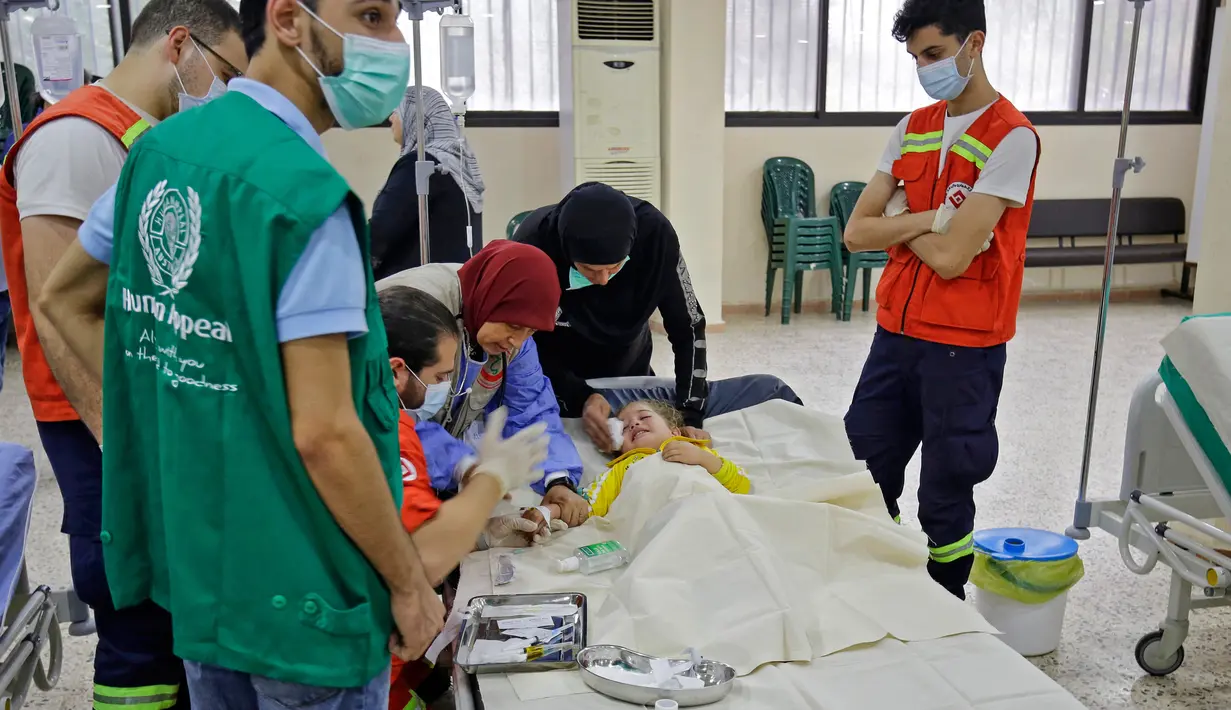 Staf medis merawat seorang pasien anak yang sedang dirawat akibat wabah Kolera di aula masjid yang diubah menjadi rumah sakit lapangan di Kota Bebnine, Distrik Akkar, Lebanon Utara, Rabu (26/10/2022). Awalnya Kementerian Kesehatan Masyarakat Lebanon memberi tahu WHO pada 6 Oktober 2022 tentang dua kasus Kolera yang dikonfirmasi laboratorium dan dilaporkan dari bagian utara negara itu. (AFP/Ibrahim Chalhoub)