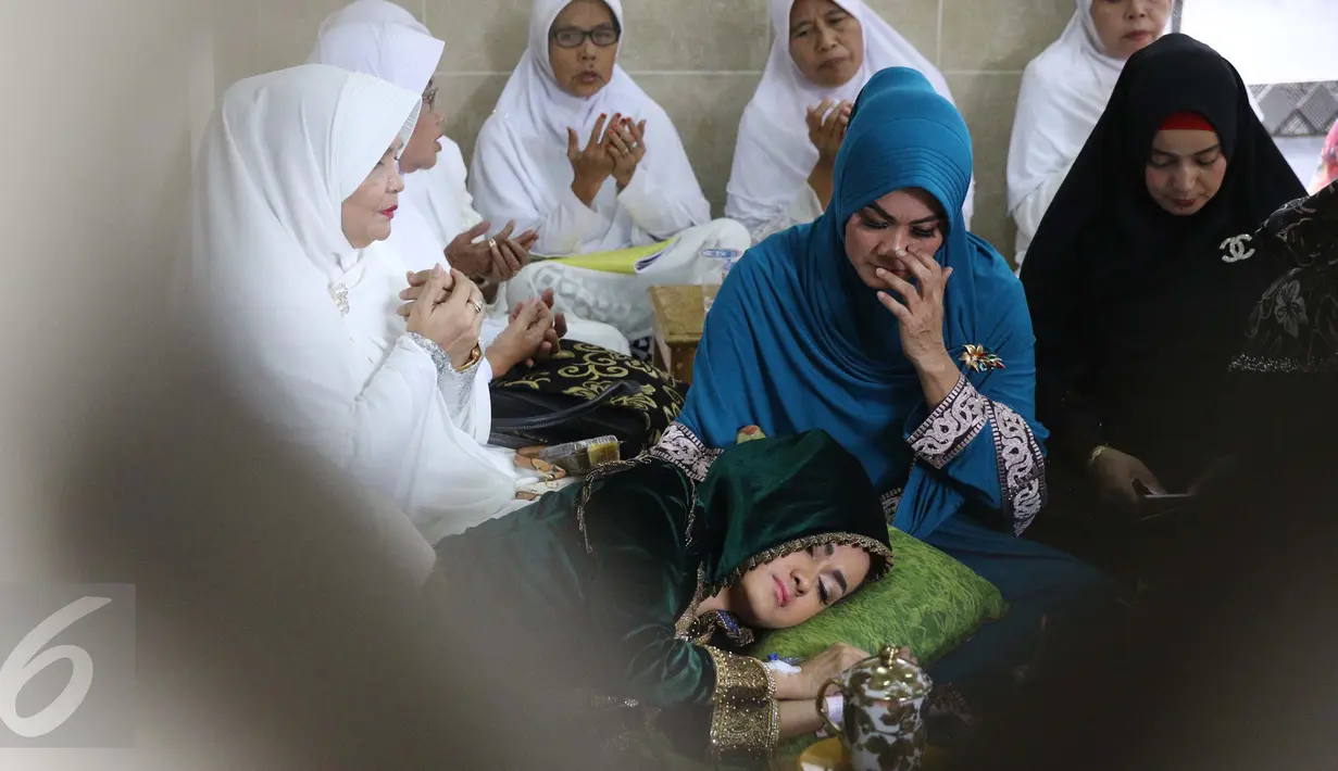 Julia Perez atau Jupe membaringkan tubuhnya di pangkuan ibunya, Sri Wulansih, disela acara pengajian di Kelapa Dua, Depok, Kamis (29/12). Bercucuran air mata,  Jupe minta didoakan sembuh dari kanker serviks yang diderita. (Liputan6.com/Herman Zakharia)