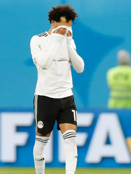 Penyerang Mesir, Mohamed Salah menutupi wajahnya usai pertandingan melawan Rusia pada grup A Piala Dunia 2018 di stadion St. Petersburg di St. Petersburg, (19/6). Rusia menang 3-1 atas Mesir. (AP Photo / Efrem Lukatsky)