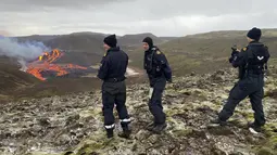 Penjaga Pantai Islandia memeriksa lava yang mengalir dari gunung berapi Fagradalsfjall yang meletus sekitar 40 km sebelah barat ibu kota Islandia, Reykjavik, pada Sabtu (20/3/2021). Sebuah gunung berapi di dekat ibu kota Islandia meletus pada hari Jumat, 19 Maret. (Icelandic Coast Guard via AP)