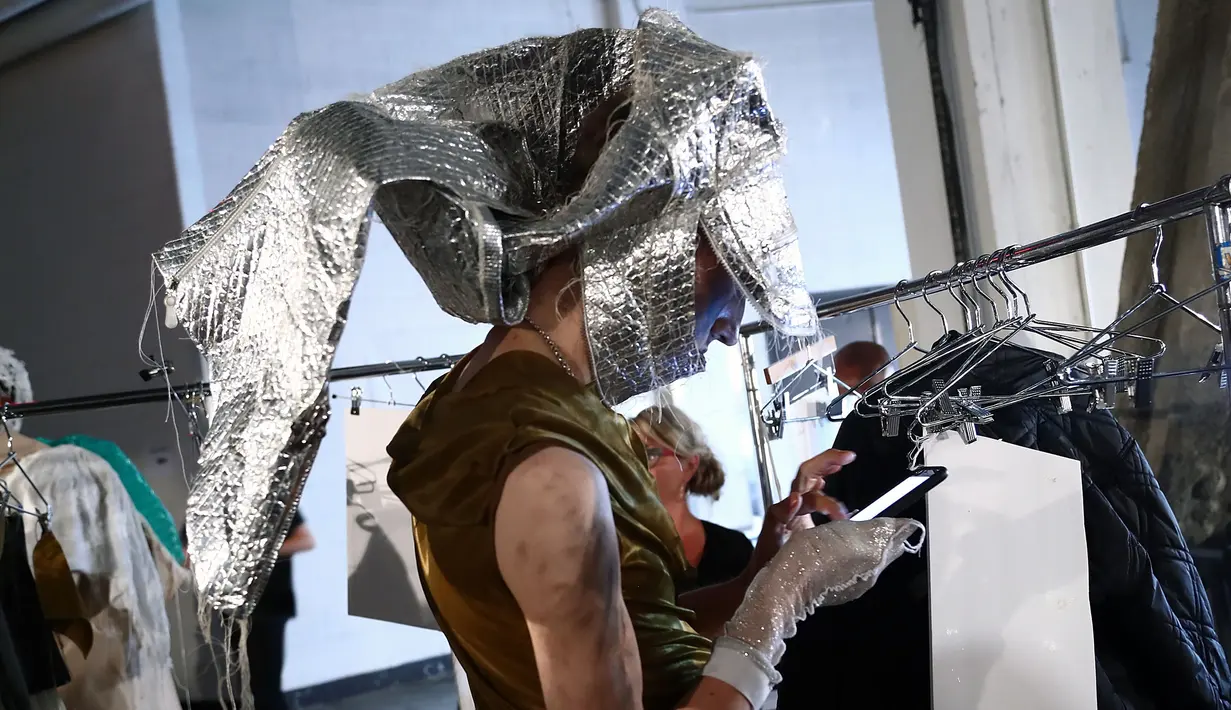Seorang model memainkan gadgetnya di belakang panggung saat bersiap membawakan busana VFILES selama New York Fashion Week di Barclays Center of Brooklyn di New York City, (6/9). (Astrid Stawiarz / Getty Images / AFP)