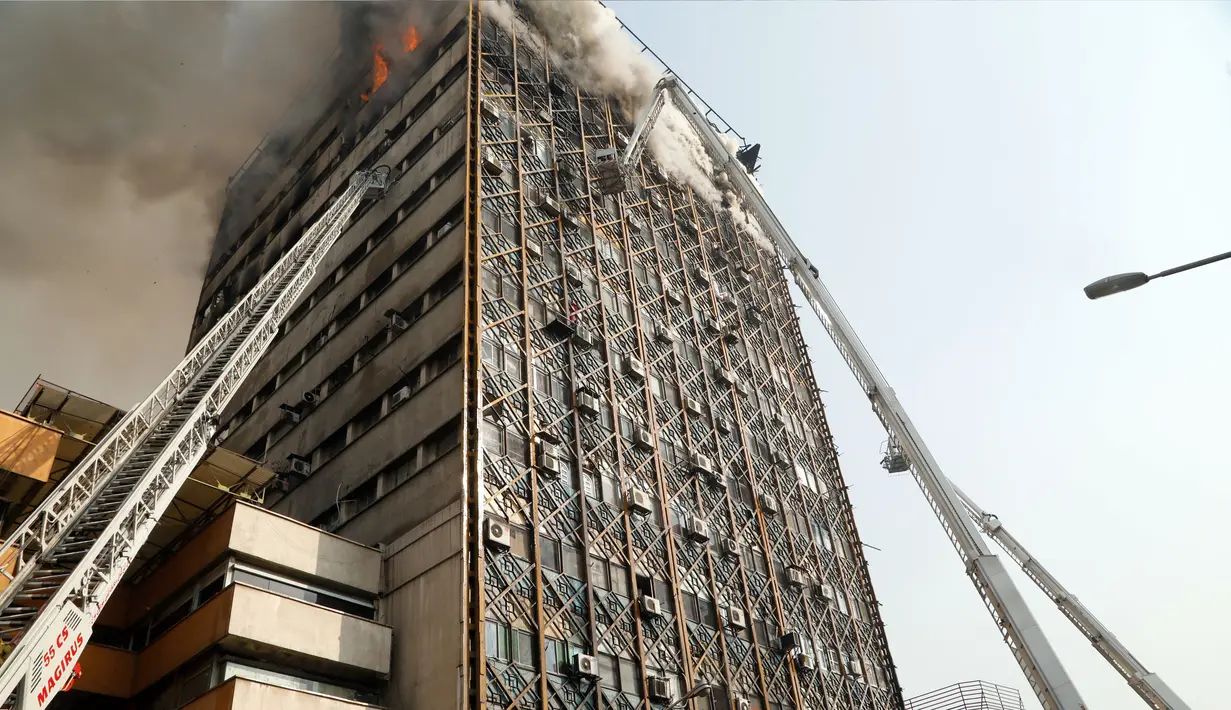 Petugas pemadam menggunakan crane mobil damkar untuk memadamkan kebakaran gedung tertua Iran, gedung Plasco, di pusat kota Teheran, Kamis (19/1). Sedikitnya 38 orang terluka akibat kebakaran di Gedung Plasco yang ikonik tersebut. (AFP PHOTO/STR)